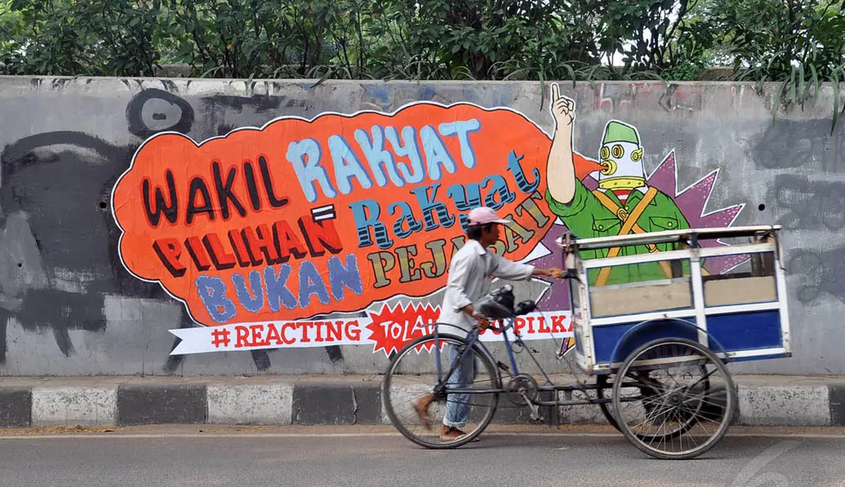 Para pengguna jalan melintasi mural Tolak RUU Pilkada di tembok fly over kawasan Pejompongan, Jakarta, (28/9/14). (Liputan6.com/Miftahul Hayat) 