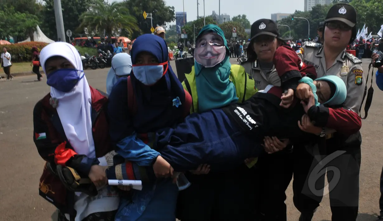 Seorang mahasiswi pingsan saat melakukan aksi unjuk rasa di depan Istana Negara, Jakarta, Kamis (21/5/2015).  Aksi tersebut menuntut agar Pemerintahan memprioritaskan masyarakat pribumi daripada asing. (Liputan6.com/Johan Tallo)