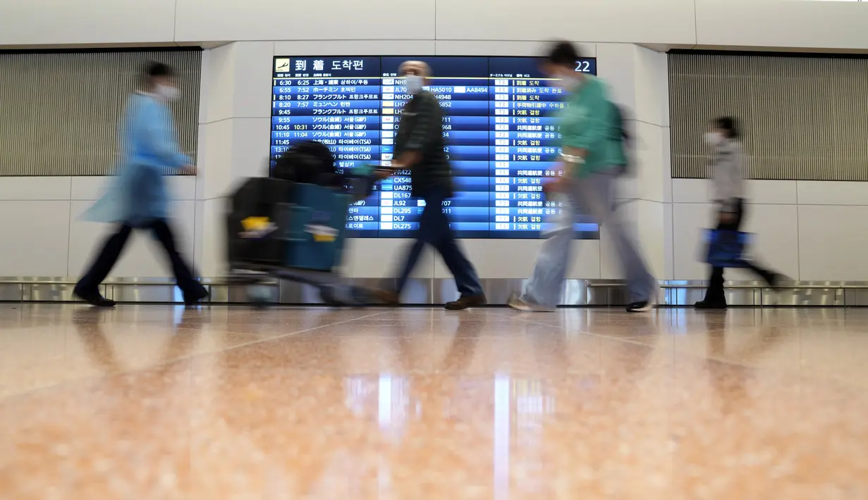 Wisatawan asing dan staf bandara berjalan di Bandara Internasional Haneda, Tokyo, Selasa (11/10/2022). Pembatasan ketat perbatasan Jepang dilonggarkan, memungkinkan wisatawan dengan mudah masuk untuk pertama kalinya sejak dimulainya pandemi COVID-19. (AP Photo/Eugene Hoshiko)