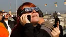 Seorang wanita menatap matahari mengenakan kacamata pelindung untuk menyaksikan Gerhana Matahari sebagian di pusat kota Skopje, Makedonia Utara, pada Selasa (25/10/2022). Peristiwa Gerhana Matahari terakhir pada tahun 2022 terlihat dari sebagian besar Eropa, serta Afrika Utara, Timur Tengah, dan Asia Barat. (AP Photo/Boris Grdanoski)