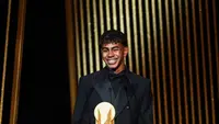 Penyerang muda Barcelona, Lamine Yamal, menerima Kopa Trophy, lambang pemenang predikat pemain muda terbaik di seremonial Ballon d'Or yang berlangsung di Theatre du Chatelet di Paris, Senin (28/10/2024) malam waktu setempat. (FRANCK FIFE / AFP)