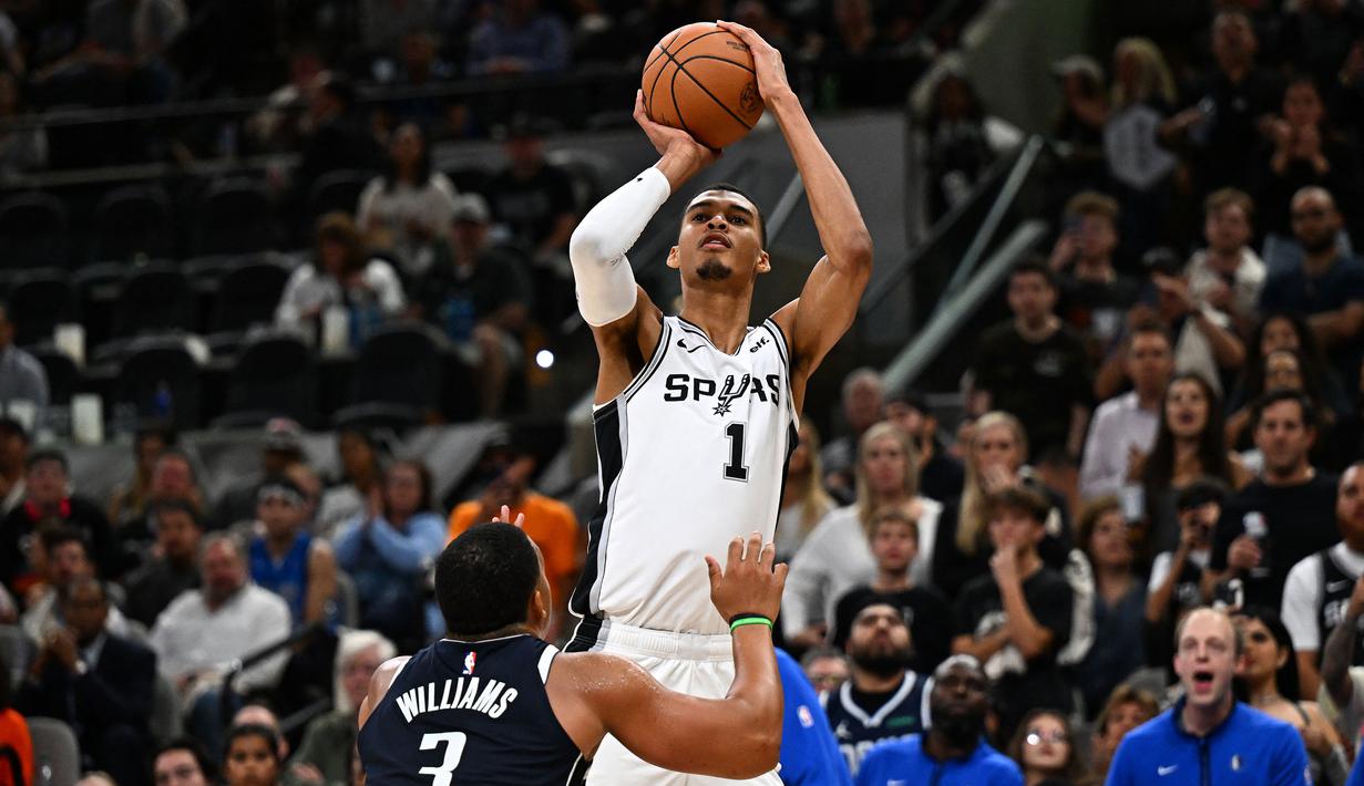 Pebasket San Antonio Spurs, Victor Wembanyama (kanan) melakukan shooting pada laga pertama NBA musim 2023/2024 melawan Dallas Mavericks di AT&T Center in San Antonio, Texas, Kamis (27/10/2023). Laga debut Wembanyama berakhir dengan kekalahan 119-126. (AFP/Chandan Khanna)