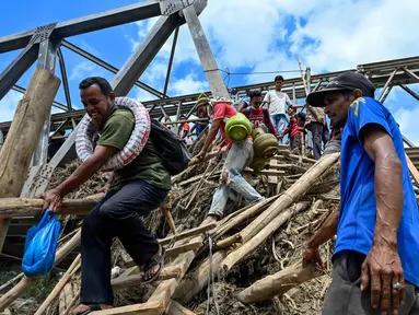 Warga menyeberangi sungai di jembatan yang baru dibangun yang menghubungkan Aceh dan Provinsi Sumatera Utara setelah hancur akibat banjir bandang di Sungai Peusangan, Bireuen, Provinsi Aceh, pada Selasa 9 Desember 2025. Sebagian jembatan rangka baja yang menghubungkan Aceh dan Provinsi Sumatera Utara di Sungai Peusangan, Bireuen, Provinsi Aceh, hancur akibat terjangan banjir bandang pada akhir November 2025 lalu. (CHAIDEER MAHYUDDIN/AFP)