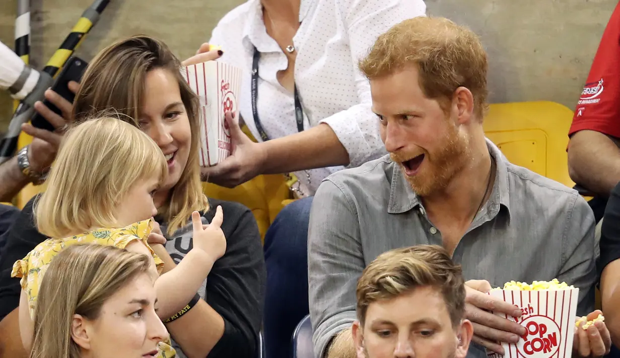 Pangeran Harry menyingkirkan popcorn saat Emily Henson hendak mengambil lagi disela acara Invictus Games 2017 di Toronto, Kanada, Rabu (27/9). Seperti merasa canggung, Emily pun mengangguk-angguk dengan menggemaskan. (CHRIS JACKSON/GETTY IMAGES/AFP)