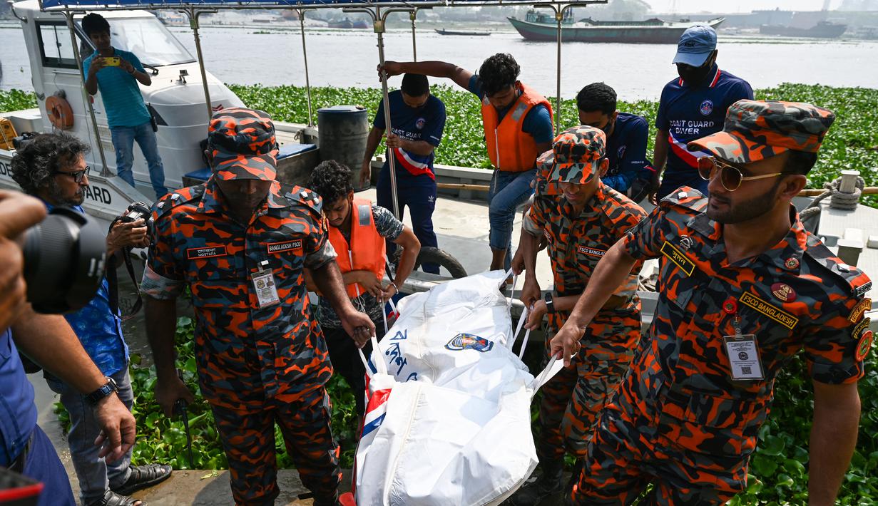 Petugas pemadam kebakaran membawa mayat korban kecelakaan feri yang ditemukan dari Sungai Shitalakshya di Narayanganj, Bangladesh (21/3/2022). Feri ML Afsar Uddin tenggelam di sungai setelah ditabrak kapal kargo. (AFP/Munir uz Zaman)
