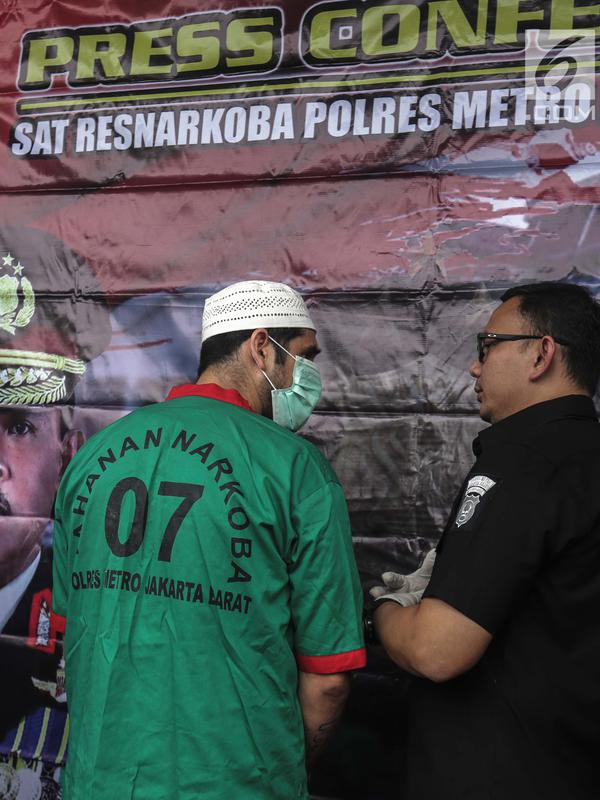 Artis Claudio Martinez memakai masker berbicang dengan Kasat Narkoba Polres Metro Jakbar AKBP Erick Frendriz  saat rilis narkoba di Polres Jakarta Barat, Jumat (9/11). Claudio ditangkap dengan barang bukti 7,96 gram ganja. (Liputan6.com/Faizal Fanani)