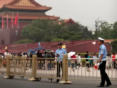 Petugas keamanan berjaga-jaga di depan Gerbang Tiananmen di sebelah Lapangan Tiananmen di Beijing (4/6/2019). Pemerintah China meningkatkan keamanan di sekitar Lapangan Tiananmen di pusat Beijing jelang peringatan tragedi Tiananmen 1989. (AP Photo/Mark Schiefelbein)