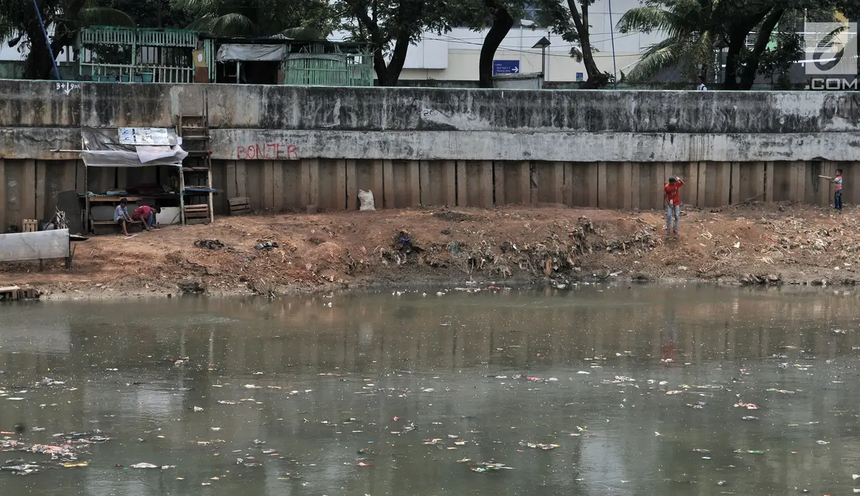 Anak-anak bermain di pinggir aliran Kanal Banjir Barat yang tengah dipenuhi sampah, Jakarta, Senin (22/10). Sampah yang memenuhi aliran kanal pencegah banjir tersebut didominasi plastik dan limbah rumah tangga. (Merdeka.com/Iqbal Nugroho)