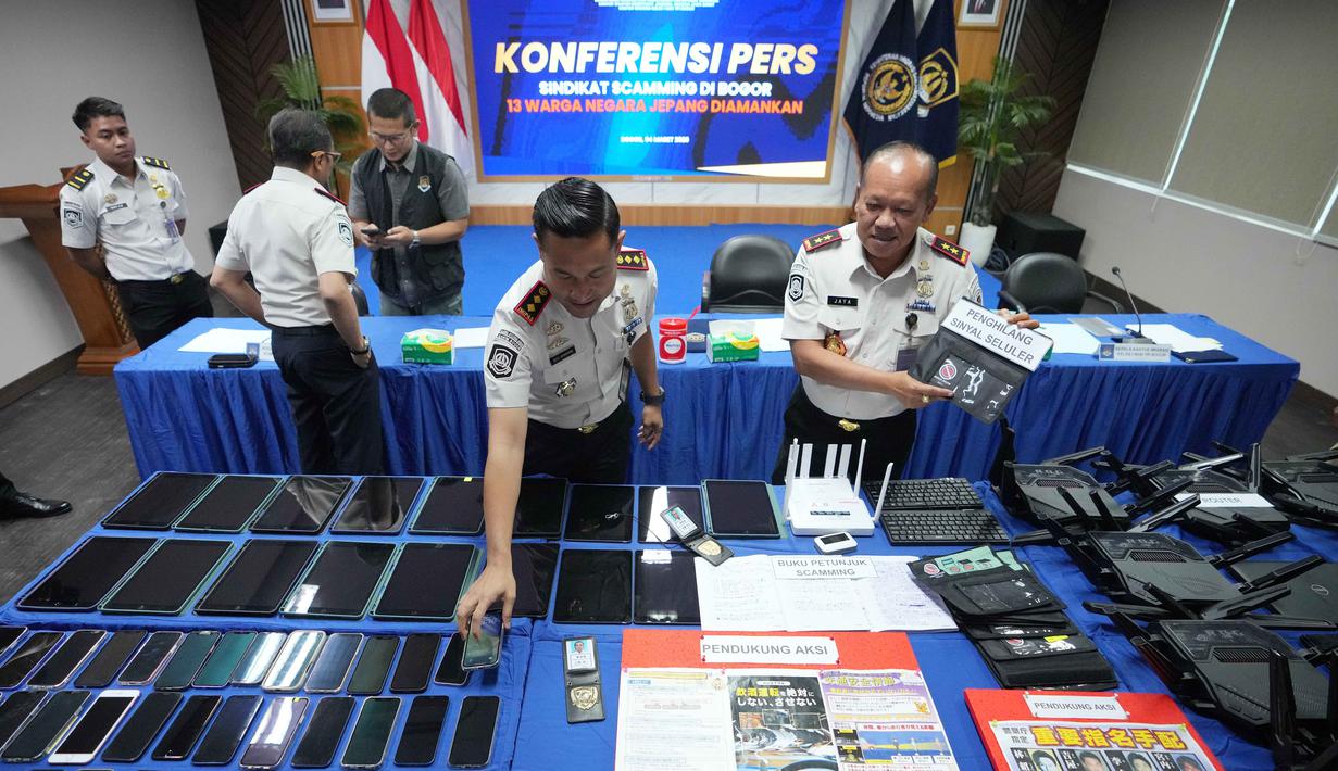 Petugas Imigrasi mengatur barang bukti yang disita dari warga negara Jepang yang diduga terlibat dalam sindikat penipuan daring (online), di Bogor, Jawa Barat, Rabu 4 Maret 2026. 13 warga negara asing atau WNA asal Jepang ditangkap petugas Kantor Imigrasi Bogor, Jawa Barat. (AP Photo/Achmad Ibrahim)