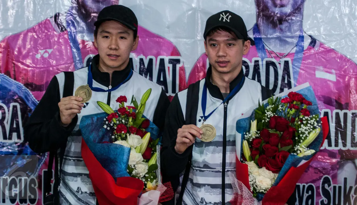 Kevin Sanjaya Sukamuljo dan Marcus Fernaldi Gideon memamerkan medalinya saat tiba di Bandara Internasional Soekarno Hatta, Tangerang, Banten, Selasa (14/3). Kevin dan Marcus adalah juara ganda putra All England 2017. (Liputan6.com/Gempur M Surya)