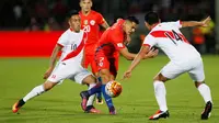 Penyerang Chile, Alexis Sanchez (tengah) berusaha melewati dua pemain Peru pada Kualifikasi Piala Dunia 2018 di National Stadium, Santiago, Chile (11/10).  Chile menang atas Peru dengan skor 2-1. (REUTERS/Rodrigo Garrido)