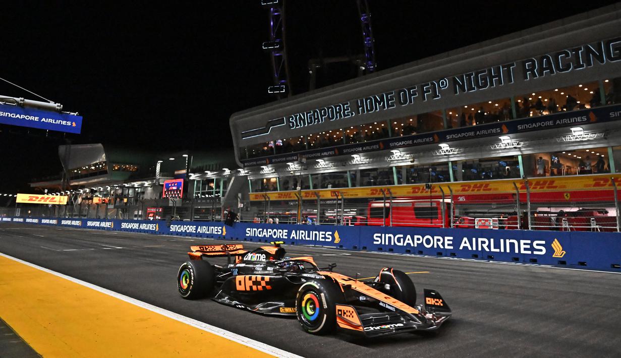 Pembalap tim McLaren, Lando Norris memacu mobilnya saat melintasi tribun dalam balapan F1 GP Singapura 2023 di Marina Bay Street Circuit, Singapura, Minggu (17/9/2023) malam WIB. (AFP/Lillian Suwanrumpha)