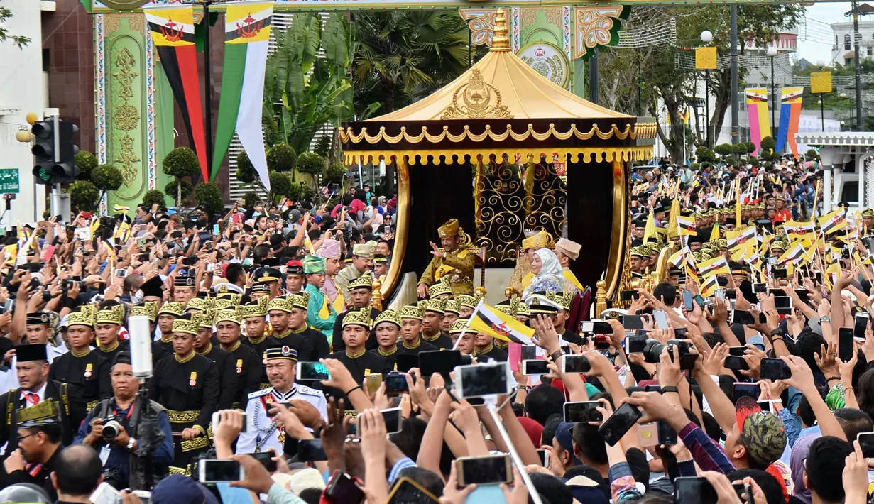 Ribuan warga mengabadikan moment kadatangan Sultan Hassanal Bolkiah dan Ratu Saleha Brunei pada prosesi Golden Jubileedi Bandar Seri Begawan (5/10). Perayaan tersebut menandai 50 tahun bertahta. (AFP PHOTO / Roslan Rahman)