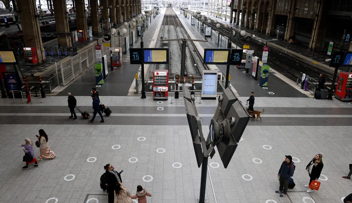 Sejumlah pelancong berjalan melewati layar informasi saat lalu lintas terganggu di stasiun kereta Gare du Nord pada hari kedua pemogokan nasional dan protes terhadap rencana reformasi pensiun pemerintah di Paris, Selasa (31/1/2023). Operator transportasi ibu kota RATP mengatakan sebagian besar layanan kereta bawah tanah dan metro Paris akan sangat dibatasi. (Ludovic MARIN/AFP)