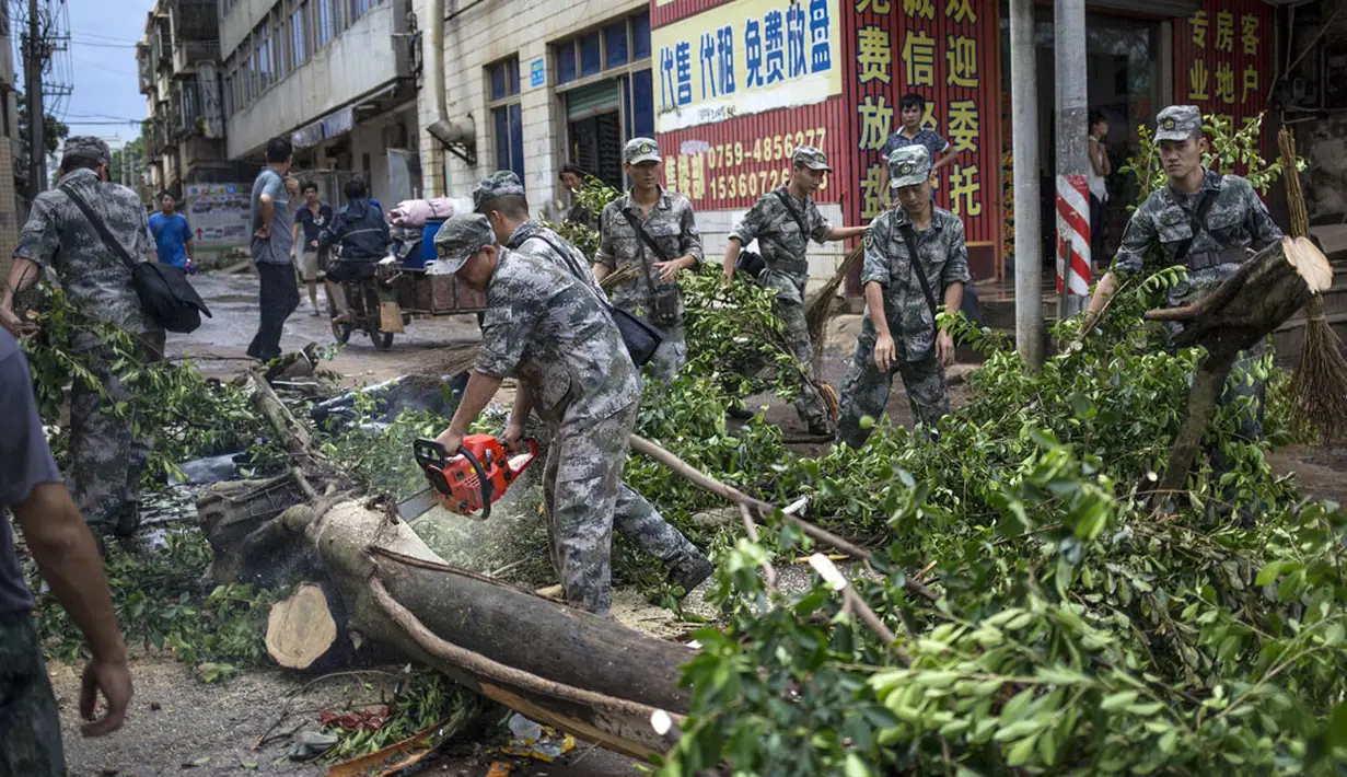 Beberapa tentara memotong batang pohon yang tumbang akibat hantaman Topan Rammasun yang memporak-porandakan kota Zhanjiang di provinsi Guangdong, (20/7/2014). (REUTERS/Stringer)