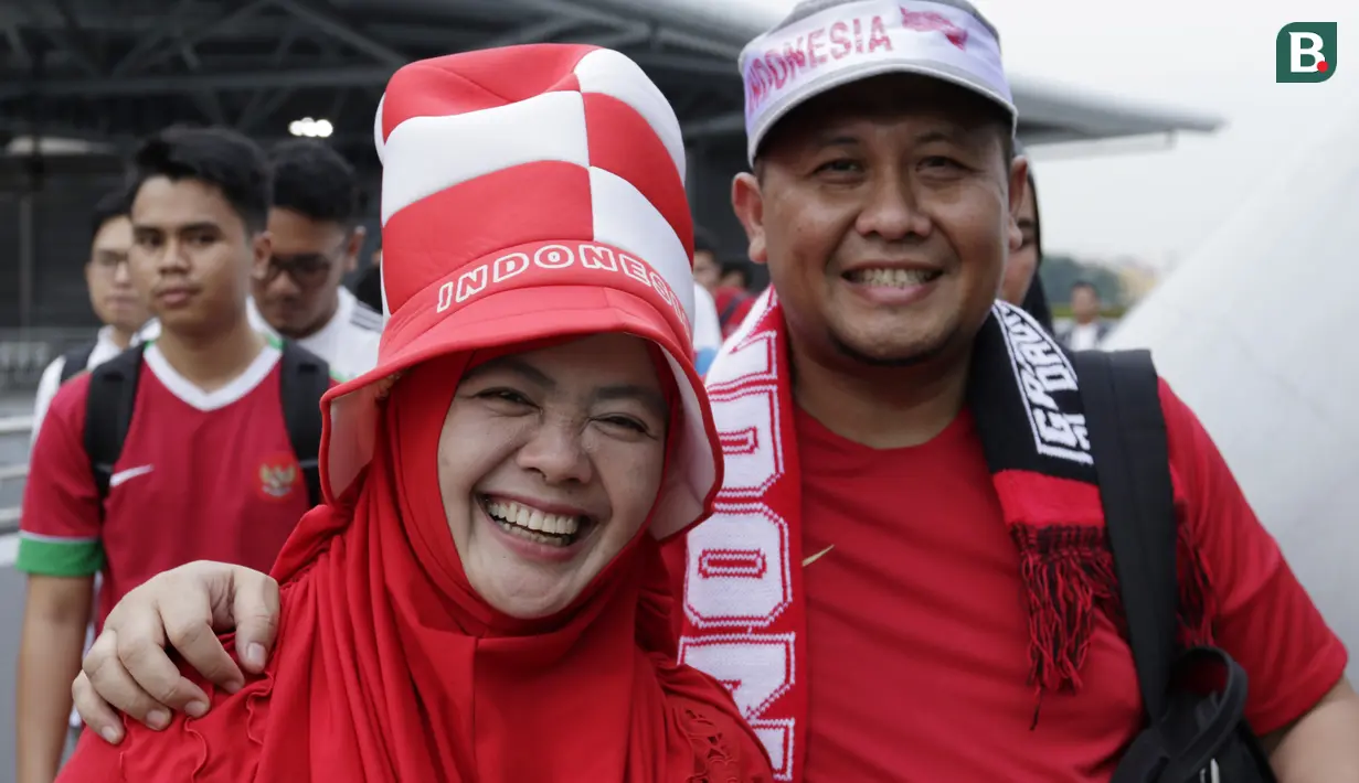 Dua suporter Timnas Indonesia tersenyum saat berada di Stadion Nasional, Singapura, Jumat (9/11). Indonesia akan melawan Singapura pada laga Piala AFF 2018. (Bola.com/M. Iqbal Ichsan)