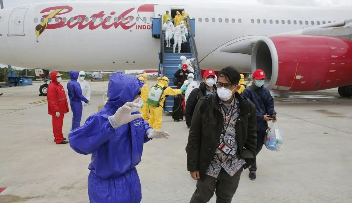 Petugas menyemprotkan cairan disinfektan ke WNI yang dievakuasi dari Wuhan, China saat tiba di bandara internasional Hang Nadim, Batam, Minggu (2/2/2020). Sebanyak 245 WNI di Wuhan dievakuasi ke Indonesia terkait merebaknya virus corona di kota tersebut. (Photo by Handout/Indonesian Embassy/AFP)