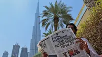 Seorang pria membaca salinan surat kabar The National dengan tajuk utama tentang perjanjian UEA-Israel di dekat Burj Khalifa, Dubai. (AFP/Giuseppe Cacace)