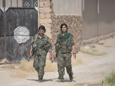 Dua prajurit perempuan Yazidi dari Unit Perlawanan Sinjar (YBS) berjalan saat patroli di sebuah jalan di wilayah Pegunungan Sinjai, Irak (6/6). (Reuters/Stringer)