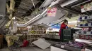Pekerja mengeluarkan barang dagangan dari rak saat plafon rusak di sebuah supermarket di Shiroishi, setelah gempa magnitudo 7,3 mengguncang timur laut Jepang, Kamis (17/3/2022). Gempa pada Rabu malam ini menyebabkan dua orang meninggal serta 94 orang alami luka-luka (Charly TRIBALLEAU/AFP)