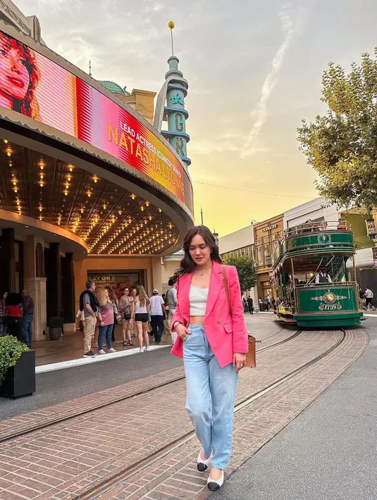 Blazer warna pink cerah dipadukan dengan crop top sebagai inner, dan high waisted jeans jadi pilihan Shandy untuk jalan-jalan sore. [Instagram/shandyaulia]