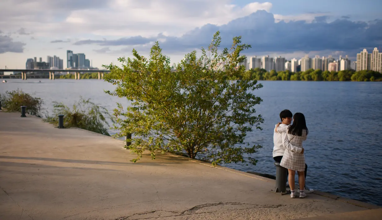 Sepasang pengunjung menikmati pemandangan sungai Han dan cakrawala Seoul pada hari terakhir liburan Chuseok di taman Yeouido, Rabu (26/9). Hari libur besar masyarakat Korea ini dirayakan setiap musim gugur tiba. (AFP PHOTO / Ed JONES)