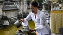 Seorang perempuan menuangkan air suci ke dalam mangkuk saat Hari Raya Galungan di sebuah pura di Bali, Rabu (4/1/2023). Perayaan Hari Galungan merupakan hari kemenangan kebenaran (Dharma) atas kejahatan (Adharma). (SONNY TUMBELAKA / AFP)