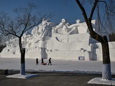 Orang-orang berjalan di samping patung salju raksasa di Pameran Seni Patung Salju Internasional Harbin Sun Island menjelang Festival Es dan Salju Internasional Harbin Tiongkok ke-39 di Harbin, di provinsi Heilongjiang timur laut China (4/1/2023). (AFP/Hector Retamal)