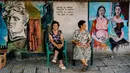 Warga duduk di depan lukisan mural seniman terkenal di  dinding desa Staro Zhelezare, Bulgaria, 4 Agustus 2018. Mural bagian dari proyek tahunan itu diluncurkan oleh wanita Polandia, Katarzyna Piriankov dan suaminya, Ventzislav. (AFP/Dimitar DILKOFF)