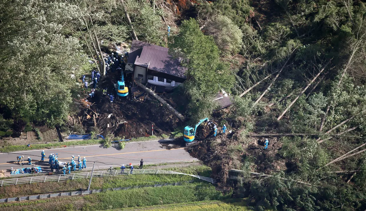 Petugas mencari korban yang selamat dari sebuah bangunan yang roboh akibat tanah longsor yang disebabkan oleh gempa di Kota Atsuma, Hokkaido, Jepang, Kamis (6/9). Akibat tanah longsor tersebut dua orang tewas dan puluhan hilang. (Kyodo News via AP)
