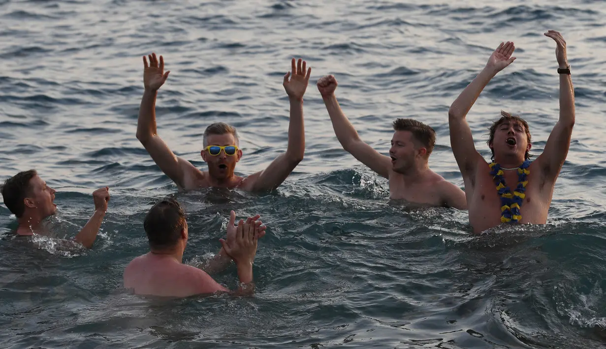 Sejumlah suporter Swedia berpesta di sekitar Pantai Sochi, Jumat (22/6/2018). Para suporter bersiap untuk menyaksikan laga Piala Dunia 2018 antara Swedia melawan Jerman. (AFP/Rebecca Blackwell)