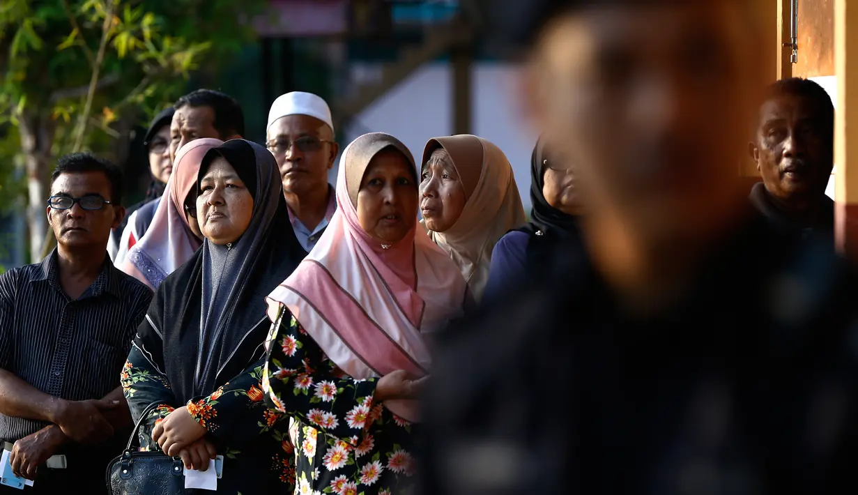 Seorang polisi berjaga saat warga Malaysia mengantre untuk menggunakan hak pilih mereka di tempat pemungutan suara (TPS) di Alor Setar, ibu kota negeri Kedah, Rabu (9/5). Pemilihan umum Malaysia ini untuk menentukan Perdana Menteri. (AP Photo/Andy Wong)