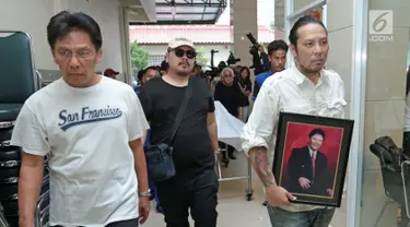 Anak Benny Panjaitan, Dino membawa foto sang ayah saat disemayamkan di rumah duka RS Dharmais, Jakarta, Selasa (24/10). Benny akan dimakamkan di TPU Menteng Pulo beberapa hari ke depan usai prosesi pemakaman adat Batak. (Liputan6.com/Herman Zakharia)