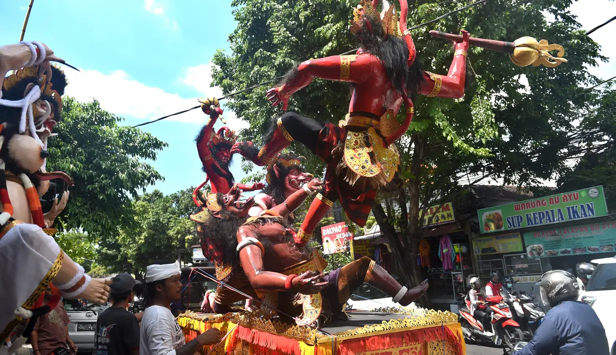Para pekerja menaruh patung atau yang dikenal ogoh-ogoh diatas mobil untuk dibawa jelang Perayaan Nyepi di Denpasar, Bali (12/3). Dalam perwujudannya ogoh-ogoh digambarkan sebagai sosok yang besar dan menakutkan. (AFP Photo/Sonny Tumbelaka)