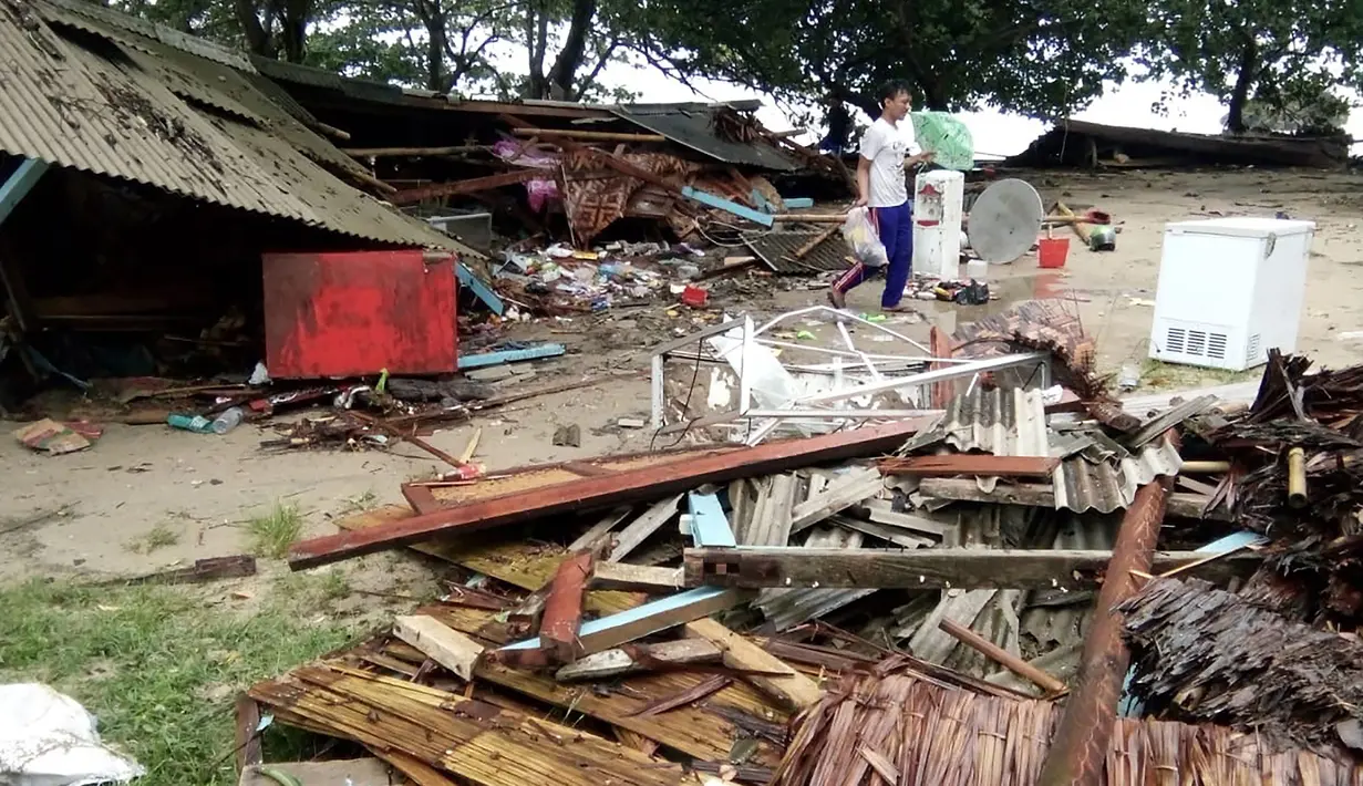 Seorang pria mencari barang-barang dari rumahnya yang rusak setelah tsunami menerjang Pantai Carita, di perairan Banten, Minggu (23/12). Tsunami menerjang beberapa daerah di sekitar Selat Sunda pada Sabtu 22 Desember 2018 malam. (SEMI / AFP)