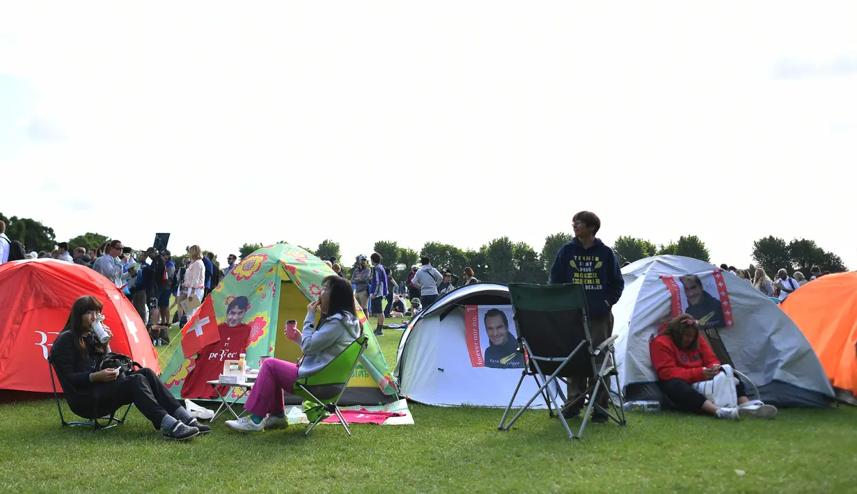 Sejumlah penonton beristirahat di tenda ketika mengantre untuk membeli tiket pada hari pertama turnamen tenis Kejuaraan Wimbledon 2019 di The All England Tennis Club di Wimbledon, London barat daya (1/7/2019). Turnamen ini dimulai 1 Juli-14 Juli 2019. (AFP Photo/Ben Stansall)