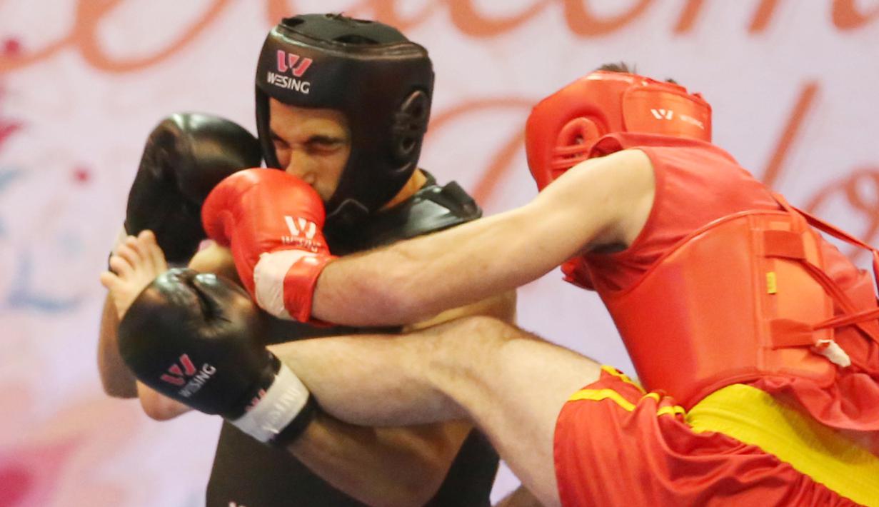 Atlet Wushu Asal Mesir, Aymen Mohamed (kiri) mendapat pukulan  Atlet Rusia, Ali  pada Cabang Sanda Kejuaraan Dunia Wushu 2015 di Istora, Senayan, Jakarta,Rabu (18/11/2015). (Bola.com/Nicklas Hanoatubun)
