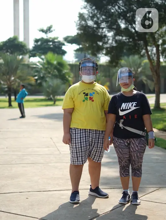Warga mengenakan masker dan pelindung wajah saat beraktivitas di sekitar Taman Lapangan Banteng, Jakarta Pusat, Sabtu (13/6/2020). Taman Lapangan Banteng kembali dibuka untuk umum namun jumlah pengunjung tetap dibatasi sebanyak 200 orang setiap pagi dan sore hari. (Liputan6.com/Immanuel Antonius)