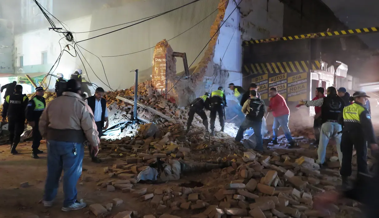 Petugas dibantu sejumlah orang mencari korban yang tertimbun puing sesaat setelah gedung bioskop tua runtuh di Tucuman, Argentina, Rabu (23/5). Sedikitnya satu orang tewas akibat kejadian tersebut. (AFP PHOTO/Walter Monteros)