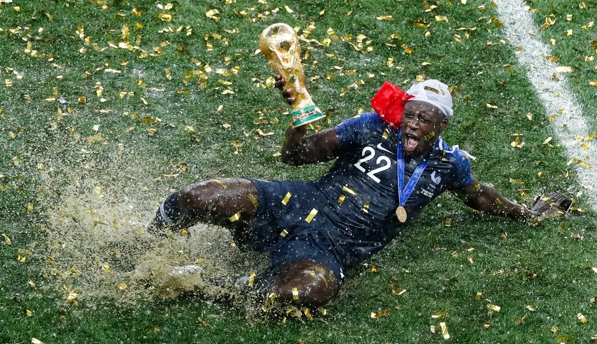Pemain timnas Prancis, Benjamin Mendy memegang trofi Piala Dunia 2018 saat merayakan gelar juara setelah mengalahkan Kroasia pada  laga final di Luzhniki Stadium, Minggu (15/7). Prancis membekuk Kroasia dengan skor akhir 4-2. (AP Photo/Rebecca Blackwell)
