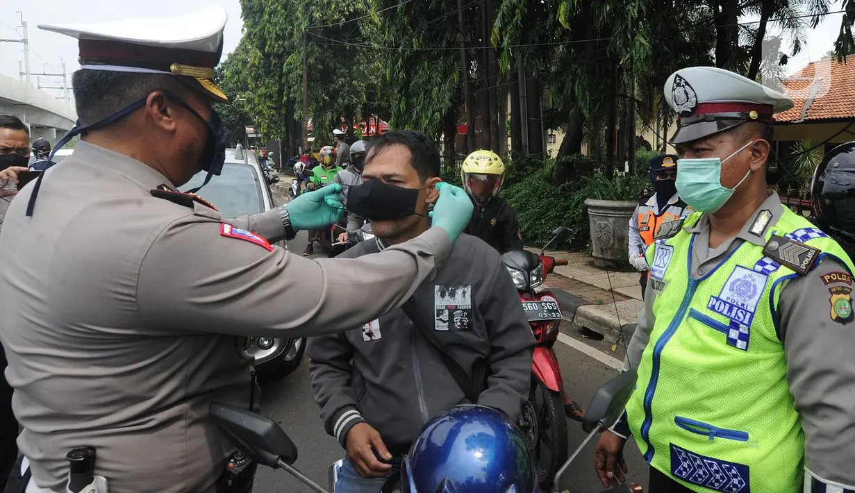 Petugas memakaikan masker ke pengendara saat kegiatan Check Point Pengawasan Pelaksaanaan PSPBB di kawasan Pasar Jumat, Jakarta selatan, Jumat (10/4/2020). Kegiatan gabungan Dishub dan Polda Metro Jaya merupakan Pergub Nomor 33 Tahun 2020 tentang Pelaksanaan PPSB. (merdeka.com/Arie Basuki)