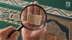 Kyai Tubagus Muhammad Tamyiz membaca Alquran mini bertinta emas dengan bantuan kaca pembesar di Masjid Jami Darusalam, Sukaraja, Bogor, Jawa Barat, Kamis (24/5). Alquran mini tersebut berukuran 10 mm x 10 mm. (Merdeka.com/Arie Basuki)