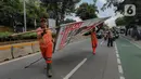 Petugas Penanganan Prasarana dan Sarana Umum (PPSU) menurunkan Alat Peraga Kampanye (APK) yang masih terpasang di kawasan Jati Padang, Jakarta, Minggu (11/2/2024). (Liputan6.com/Herman Zakharia)