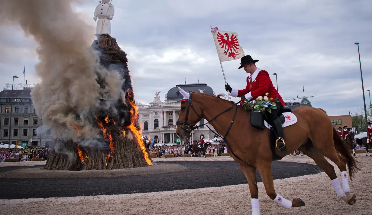 Anggota guild mengitari Boeoegg (manusia salju) yang terbakar di alun-alun Sechselaeuten, Zurich, Swiss (16/4). Acara ini untuk menandakan akhir dari festival musim dingin. (Ennio Leanza/Keystone via AP)