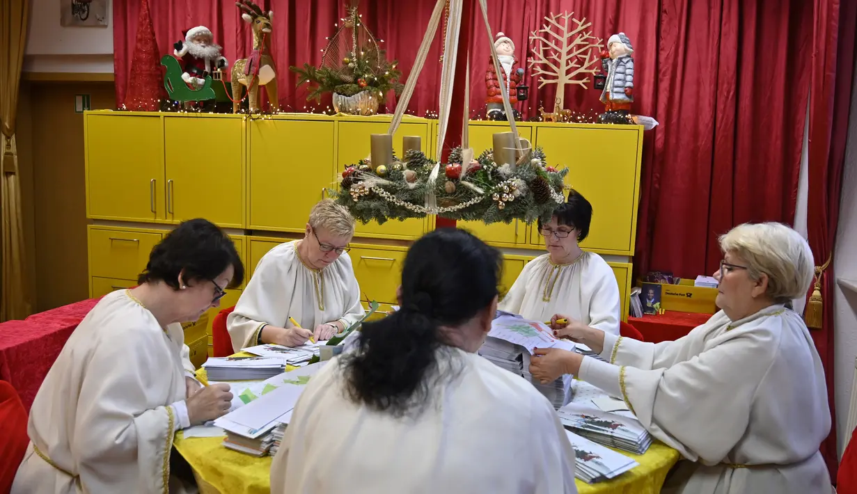Sejumlah perempuan berkostum asisten sinterklas menjawab daftar keinginan anak-anak di Kantor Pos Natal di Himmelpfort, Jerman, 19 Desember 2018. Menjelang Natal, kantor pos ini kewalahan menerima surat dari anak-anak seluruh dunia. (Tobias SCHWARZ/AFP)