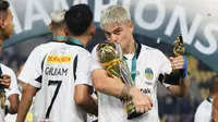Pemain PSIM Yogyakarta, Rafinha mencium trofi Pegadaian Liga 2 2024/2025 setelah timnya berhasil menang atas Bhayangkara FC dalam laga final yang berlangsung di Stadion Manahan, Solo, Jawa Tengah, Rabu (26/02/2025). (Bola.com/Abdul Aziz)