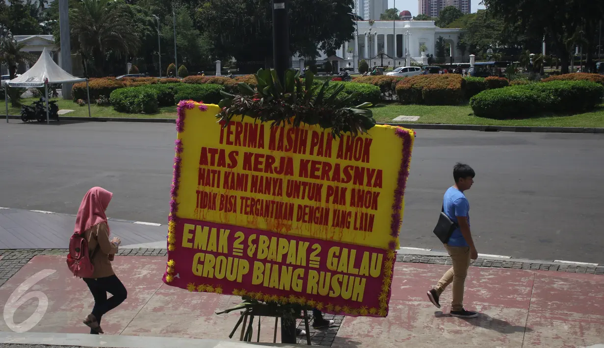 Warga berjalan di dekat karangan bunga untuk Ahok-Djarot di Taman Pandang Istana, Jakarta, Sabtu (29/4). Kiriman ribuan karangan bunga yang sebelumnya terpajang di Balai Kota Jakarta kini sudah mejalar ke depan Istana Merdeka. (Liputan6.com/Angga Yuniar)