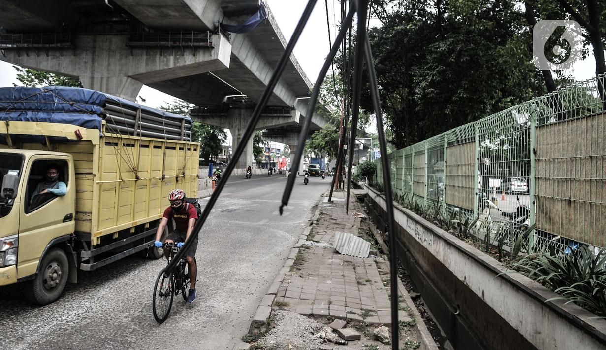 Kendaraan melintas dekat instalasi kabel yang semrawut di Jalan Raya Bekasi, Cakung, Jakarta, Rabu (30/9/2020). Minimnya perawatan pascapembebasan lahan permukiman untuk proyek Tol Dalam Kota membuat jaringan kabel listrik di sepanjang jalan tersebut semrawut. (merdeka.com/Iqbal S. Nugroho)