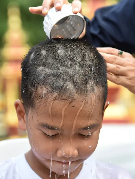 Anggota keluarga mencukur rambut seorang anak, yang diselamatkan dari gua di Thailand, pada upacara pentahbisan di Kuil Wat Phra That Doi Wao, Selasa (24/7). Sebanyak 11 remaja menjalani ritual menjadi biksu. (Panumas Sanguanwong/THAI NEWS PIX/AFP)