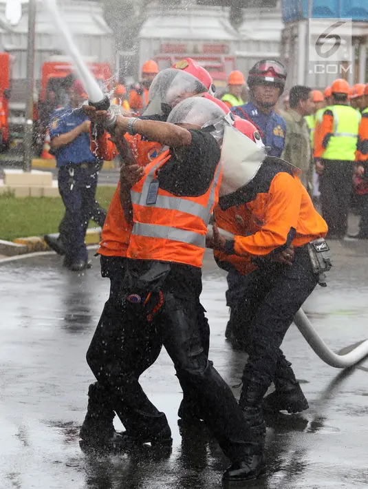 Pemadam kebakaran menyemprotkan air ke dalam gedung saat simulasi bencana di Gedung Graha BNPB, Jakarta, Kamis (26/4). (Liputan6.com/Arya Manggala)
